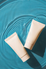 white tubes for cream cosmetic products lie on a blue background in water
