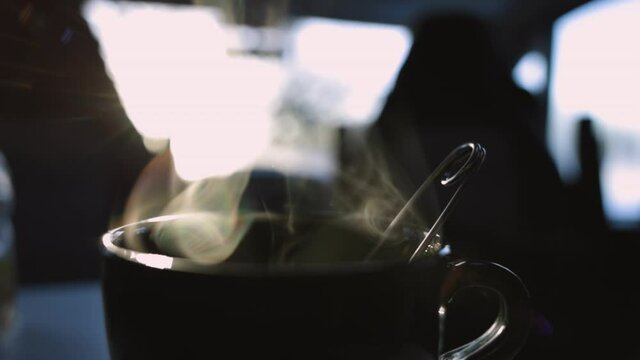 Tasse de thé chaude fumante le matin au lever du soleil dans un van, montrant la vapeur s'échapper au ralenti.