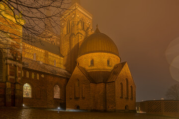 Fototapeta premium The illuminated Roskilde Cathedral a misty night