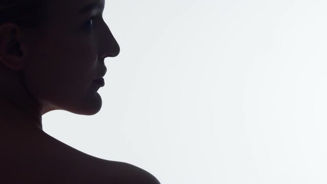 Closeup silhouette nape of woman on white background in studio, turns head to side showing beautiful face with healthy skin. Beautiful female face with well-groomed skin