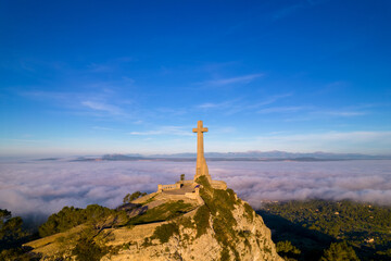 foto de la cruz de san salvador con la niebla de fondo en la isla de majorca  - obrazy, fototapety, plakaty