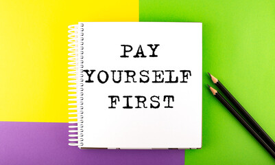 Minimal work space : sketchbook on the colorful background with Pay Yourself First text