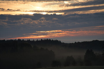 Rising sun on foggy meadow in the morning in Saarland. The sky seems to burn