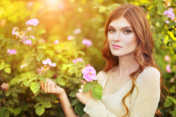 Portrait of beautiful young woman posing by rose bush