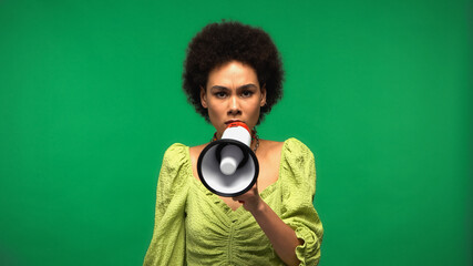 african american woman holding megaphone and looking at camera isolated on green