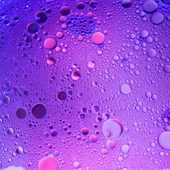 Lilac oil bubbles on water, abstract background