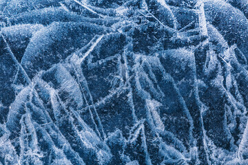 Picturesque patterns of cracks and air bubbles on the turquoise ice of the frozen Lake Baikal. Russia, Western Siberia