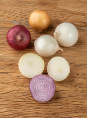 Assorted onions with halves over wooden table