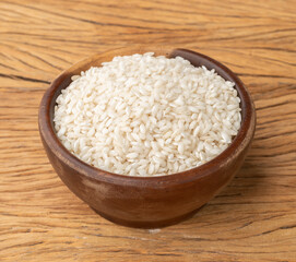 Raw carnaroli risotto rice in a bowl over wooden table