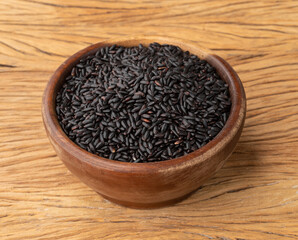 Raw black rice in a bowl over wooden table