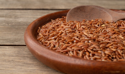 Narrow focus, raw red rice in a plate over wooden table