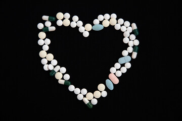 A heart made of pills on a black background. The concept of vaccination and health protection