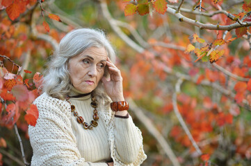 Portrait of sad senior woman in autumn park