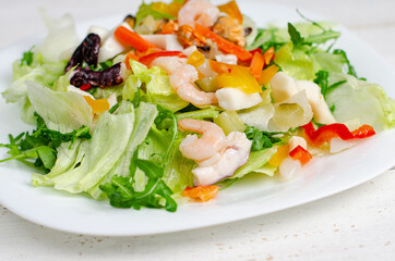 Seafood salad with vegetables and lettuce on white plate. Mediterranean delicacy diet food.