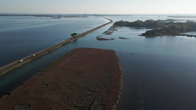 Aerial view of vehicles driving on a beautiful road crossing the lagoon in Grado near Gorizia, Friuli Venezia Giulia, Italy.