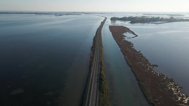 Aerial view of vehicles driving on a beautiful road crossing the lagoon in Grado near Gorizia, Friuli Venezia Giulia, Italy.
