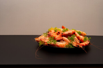 Appetizing Shrimp beautifully decorated with parsley in a plate on the black background, top view