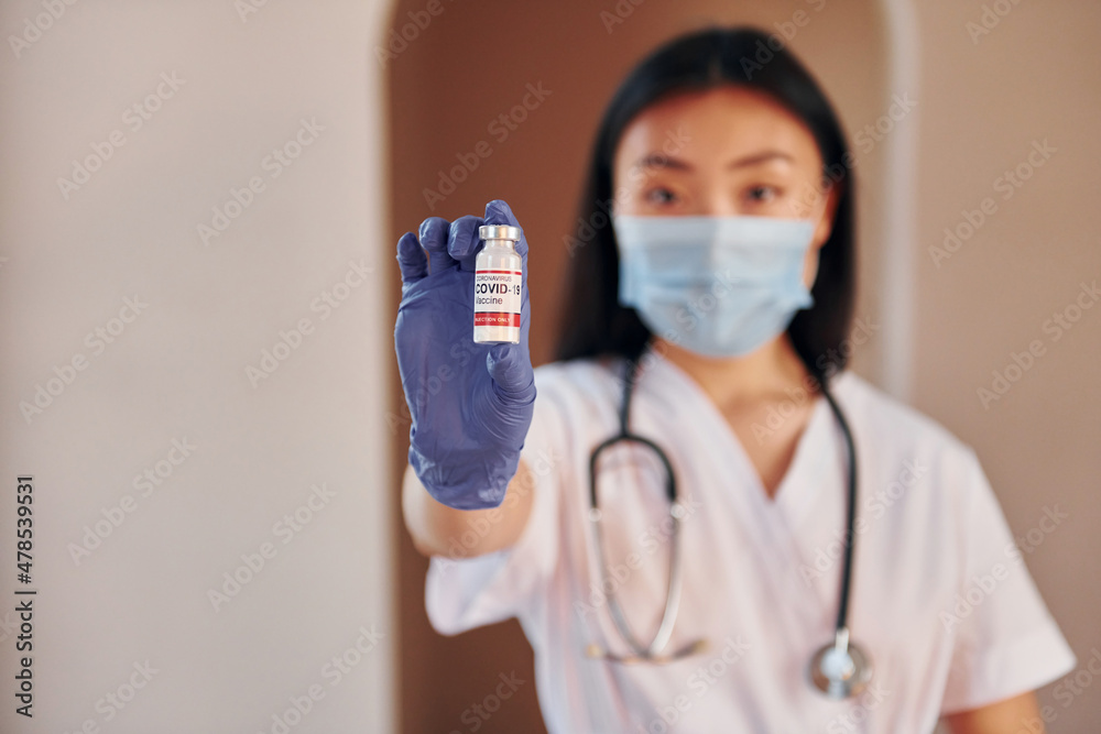 Wall mural COVID-19 vaccine. Young serious asian woman standing indoors