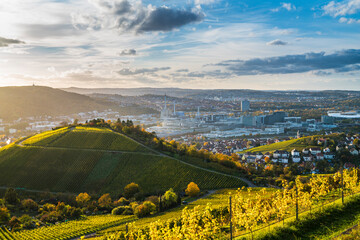 Germany, Stuttgart city panorama landscape view above vineyards into industrial quarter and arena at sunset - obrazy, fototapety, plakaty