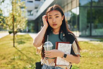 Standing on the grass. Young asian woman is outdoors at daytime