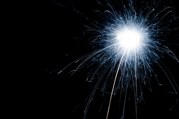 New Year's Eve celebration with a sparkler, with copy space on black background.