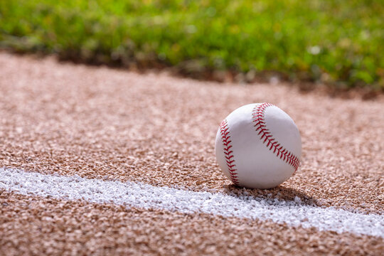 Low angle selective focus view of a baseball on a basepath in sunlight
