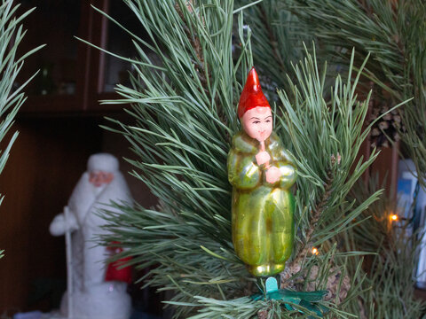 Christmas toy doll - a boy with a flute authentic old Soviet 1070s glass Christmas tree toy on a clothespin is on a spruce branch, close-up.