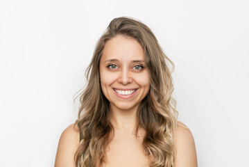 Portrait of a young attractive happy caucasian smiling blonde woman with wavy hair isolated on a white background. Charming cheerful girl with green eyes