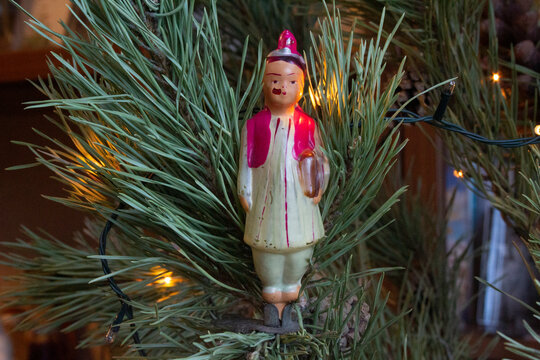 Christmas toy doll - Tajik girl authentic old Soviet 1070s glass Christmas tree toy on a clothespin on a spruce branch close-up.