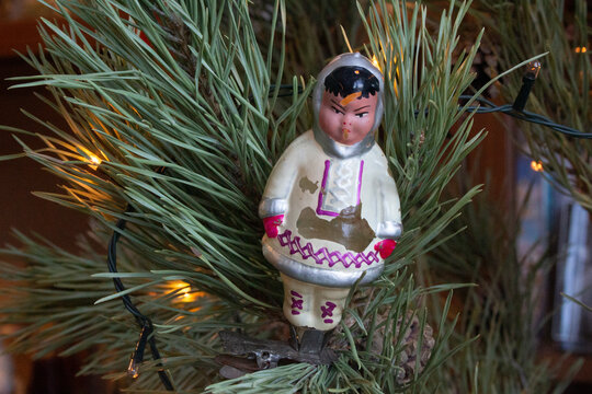 Christmas toy doll - northern girl authentic old Soviet 1070s glass Christmas tree toy on a clothespin on a spruce branch close-up.