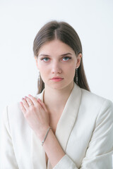 Trending silver jewelry set on a beautiful young girl in a white fashionable jacket  with long dark hair. Beauty and fashion 
