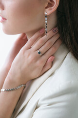 Trending silver jewelry set on a beautiful young girl in a white fashionable jacket  with long dark...