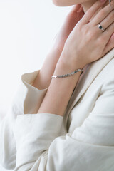 Trending silver jewelry set on a beautiful young girl in a white fashionable jacket  with long dark hair. Beauty and fashion 
