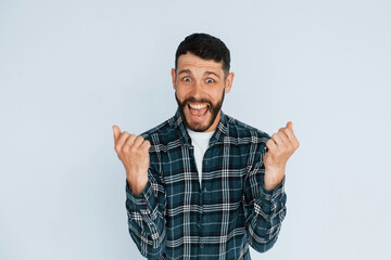 Celebrating success. Young man in casual clothes standing indoors in the studio