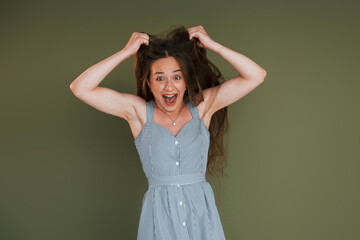 Emotional young woman in casual clothes standing indoors in the studio