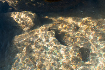 Sunrays reflecting from stones and rocks underwater - creating beautiful abstract natural pattern. Image shot at Reshi river, Sikkim, India