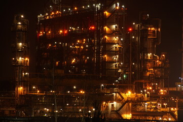 Fototapeta na wymiar Technological installation at an oil refinery. Lighting of factory equipment at night. The light from the lamps at the enterprise. 