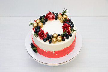 Сake decorated with golden balls, berries, pomegranate, rosemary. New Year's or Christmas dessert.