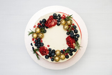 Сake decorated with golden balls, berries, pomegranate, rosemary. New Year's or Christmas dessert. Top view.