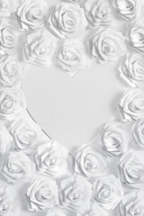 White fabric roses surrounding a love heart shaped blank textured paper for copy space