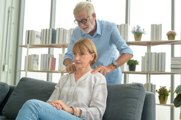 Senior caucasian man doing massage for his wife in living room