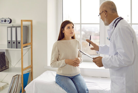 Experienced senior doctor at modern clinic talking to nervous female patient. Supportive adult physician trying to calm down worried young woman and asking her to relax before medical exam
