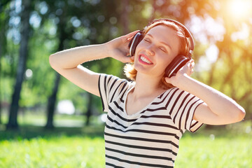 Young woman happens to have music in a summer park