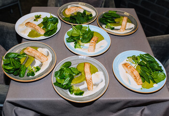 A piece, a steak of baked fish with avocado, spinach sauce and green lettuce are on a plate. A beautiful, tasty dish in the restaurant.
