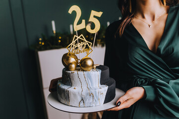 A beautiful brunette girl is holding a boring two-tiered cake with writing, congratulations on her...