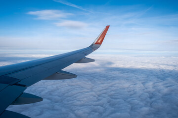Obraz premium Classic image through aircraft window onto wing. Flight view over clouds