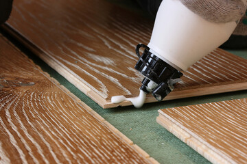 Applying glue to the ends of the parquet before laying it on the substrate - obrazy, fototapety, plakaty