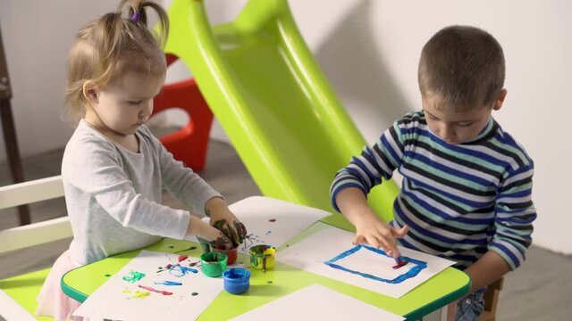 Children of different ages paint with finger paints in kindergarten or home. Concept of child development.