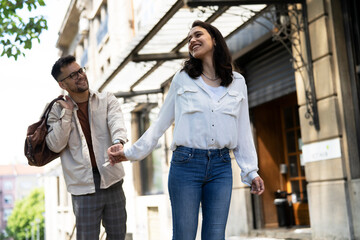 Husband and wife outdoors. Girlfriend and boyfriend walking in the city. Couple enjoy in sunny day.