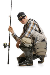 Portrait of young man, professional fisherman with fishing rod, spinning and equipment sitting isolated over white studio background